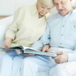 Senior couple on couch looking at book